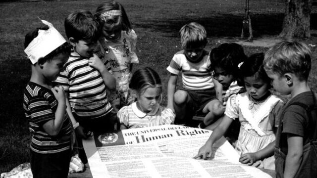 Kids pointing at a document about human rights, black and white picture